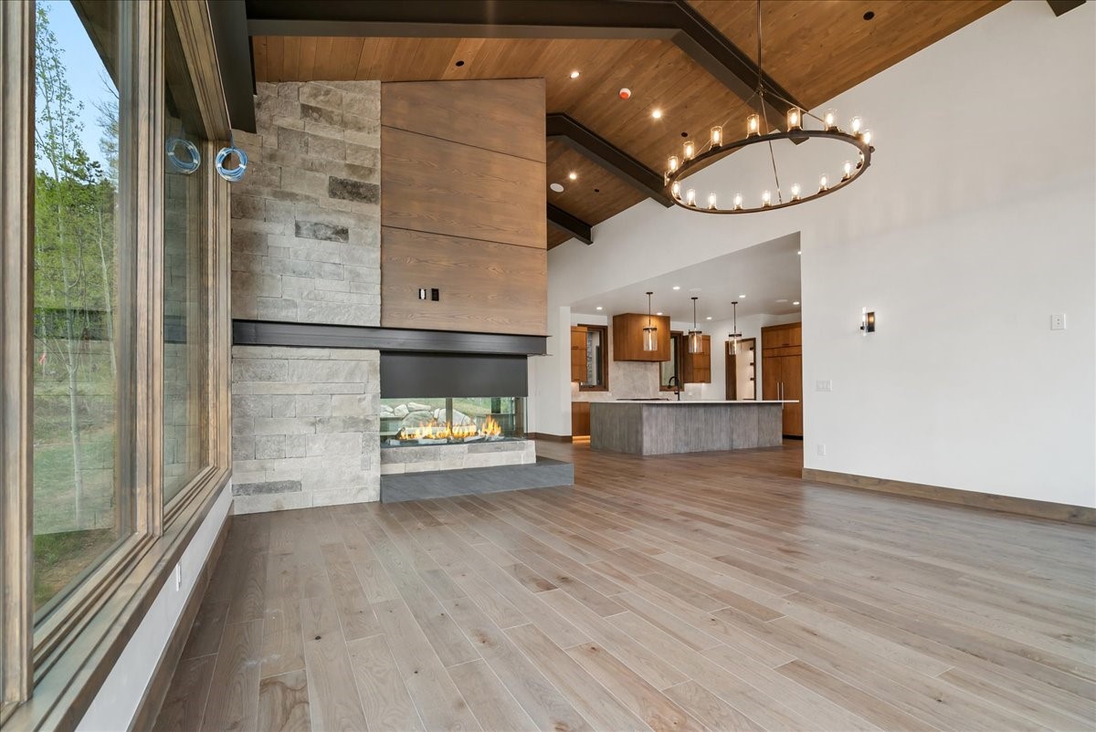 1615 Golden Eagle Road Silverthorne, CO 80498 - Photo 14 of 47 an empty room with wooden floor fireplace and chandelier