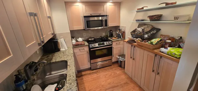 a kitchen with stainless steel appliances granite countertop a sink a stove and cabinets