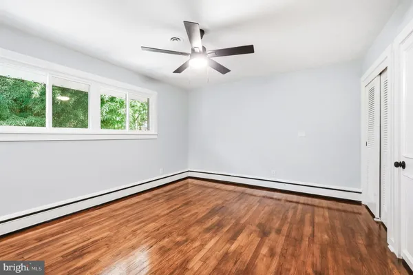 an empty room with wooden floor fan and windows
