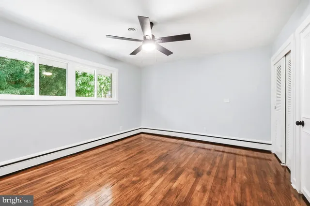 an empty room with wooden floor fan and windows