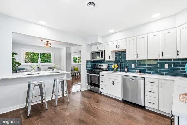 a kitchen with white cabinets and chairs