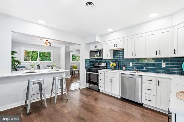 a kitchen with white cabinets and chairs