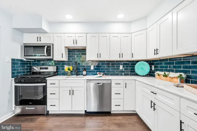 a kitchen with white cabinets appliances and a sink