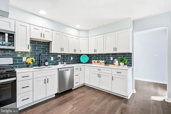 a kitchen with stainless steel appliances granite countertop white cabinets a stove a sink and dishwasher with wooden floor