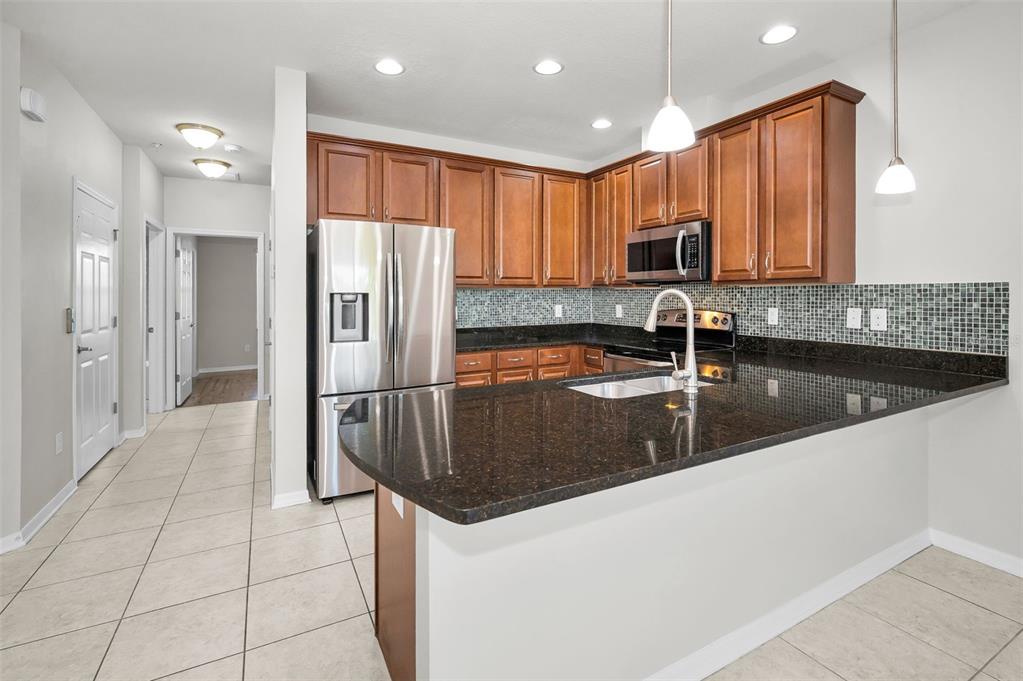 5032 Sand Castle Drive New Port Richey, FL 34652 - Photo 26 of 87 a kitchen with stainless steel appliances granite countertop a sink refrigerator and cabinets