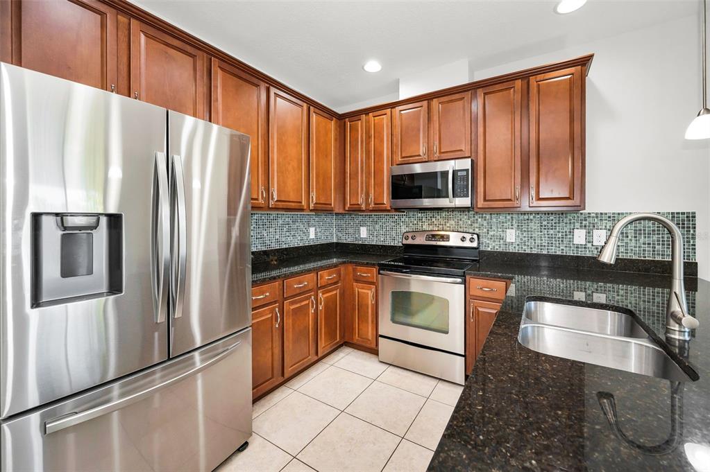 5032 Sand Castle Drive New Port Richey, FL 34652 - Photo 27 of 87 a kitchen with granite countertop wooden cabinets a refrigerator and a sink