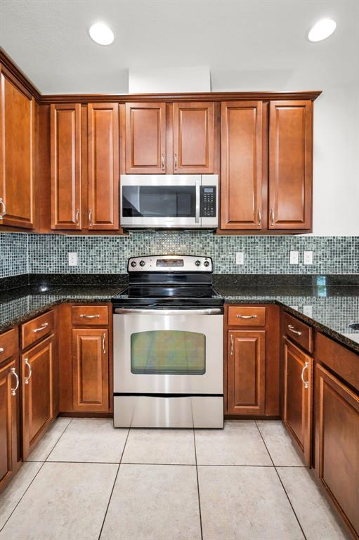 5032 Sand Castle Drive New Port Richey, FL 34652 - Photo 28 of 87 a kitchen with granite countertop a stove top oven microwave and cabinets
