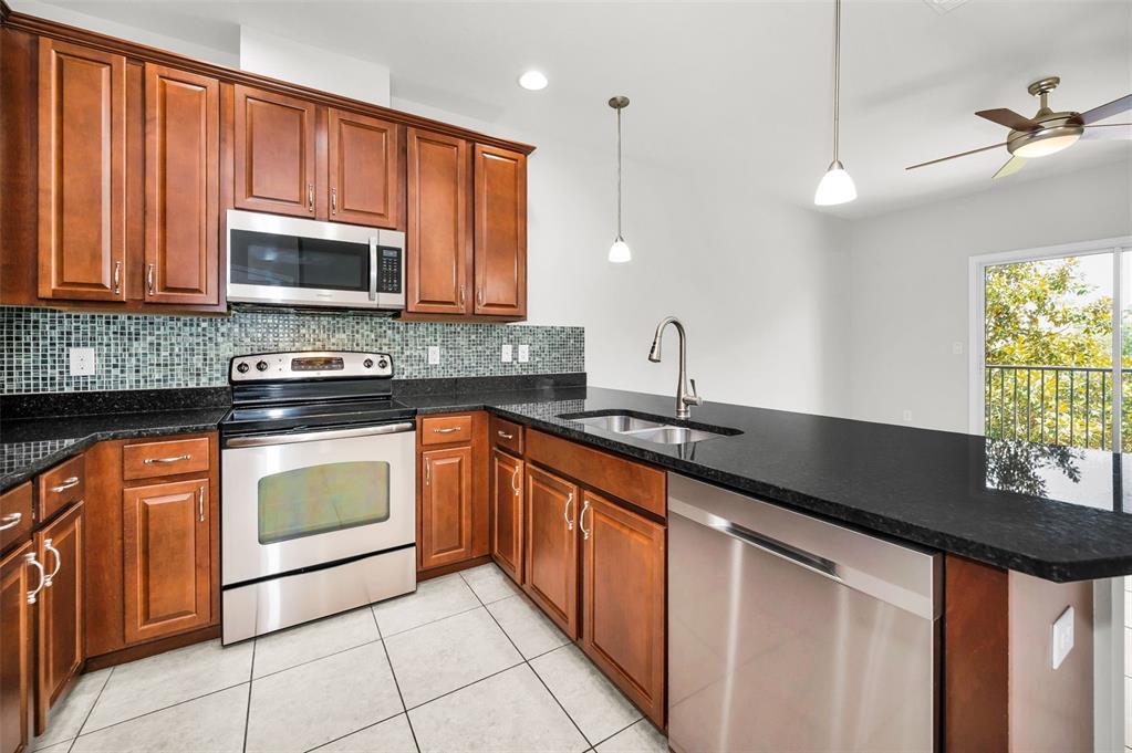 5032 Sand Castle Drive New Port Richey, FL 34652 - Photo 29 of 87 a kitchen with stainless steel appliances granite countertop a sink stove and microwave
