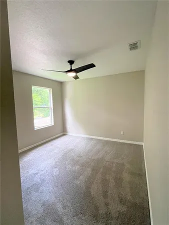 an empty room with windows and ceiling fan view