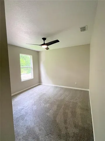an empty room with windows and ceiling fan view