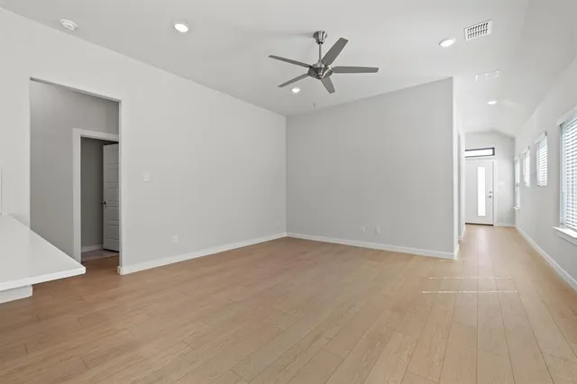 an empty room with wooden floor and a ceiling fan