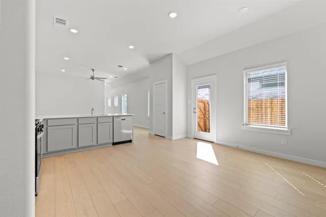 a view of an empty room with window and wooden floor