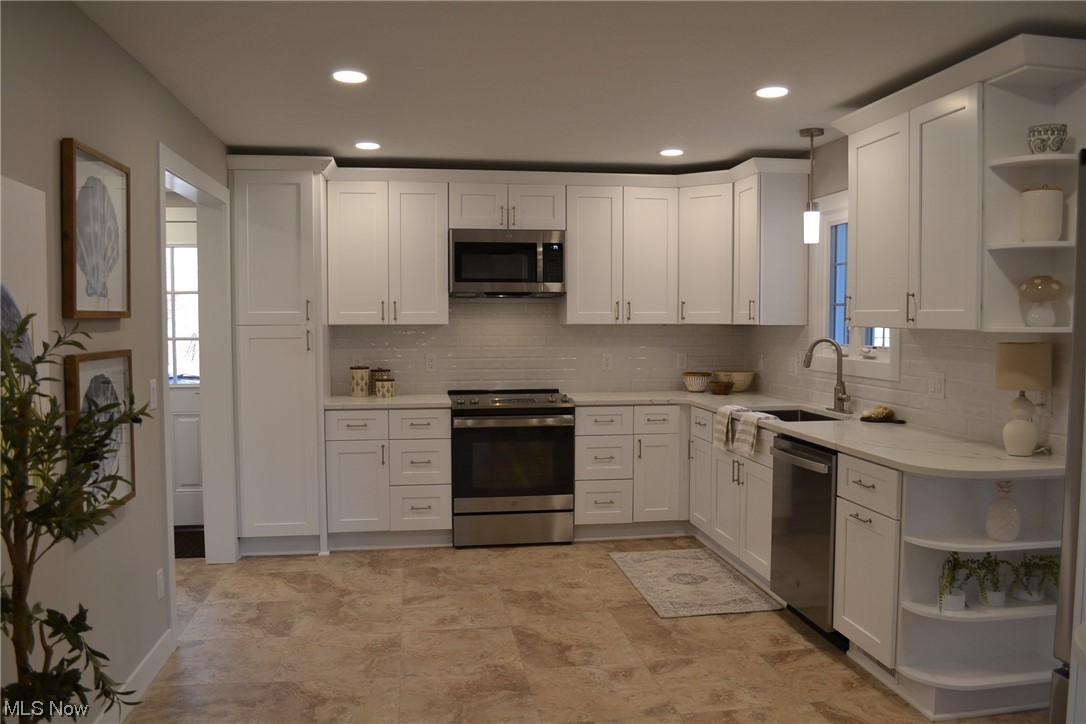 3693 Stoer Road Shaker Heights, OH 44122 - Photo 8 of 35 Kitchen featuring light tile floors, stainless steel appliances, a healthy amount of sunlight, white cabinets, and tasteful backsplash