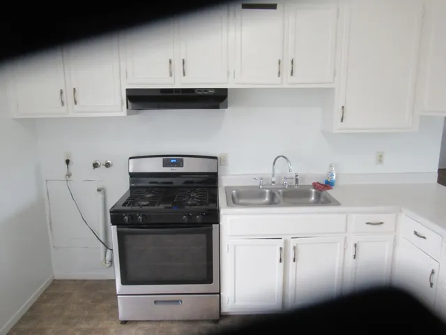 a kitchen with white cabinets and black appliances