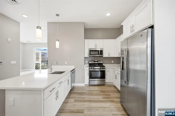 a kitchen with stainless steel appliances granite countertop a refrigerator a sink a stove and oven