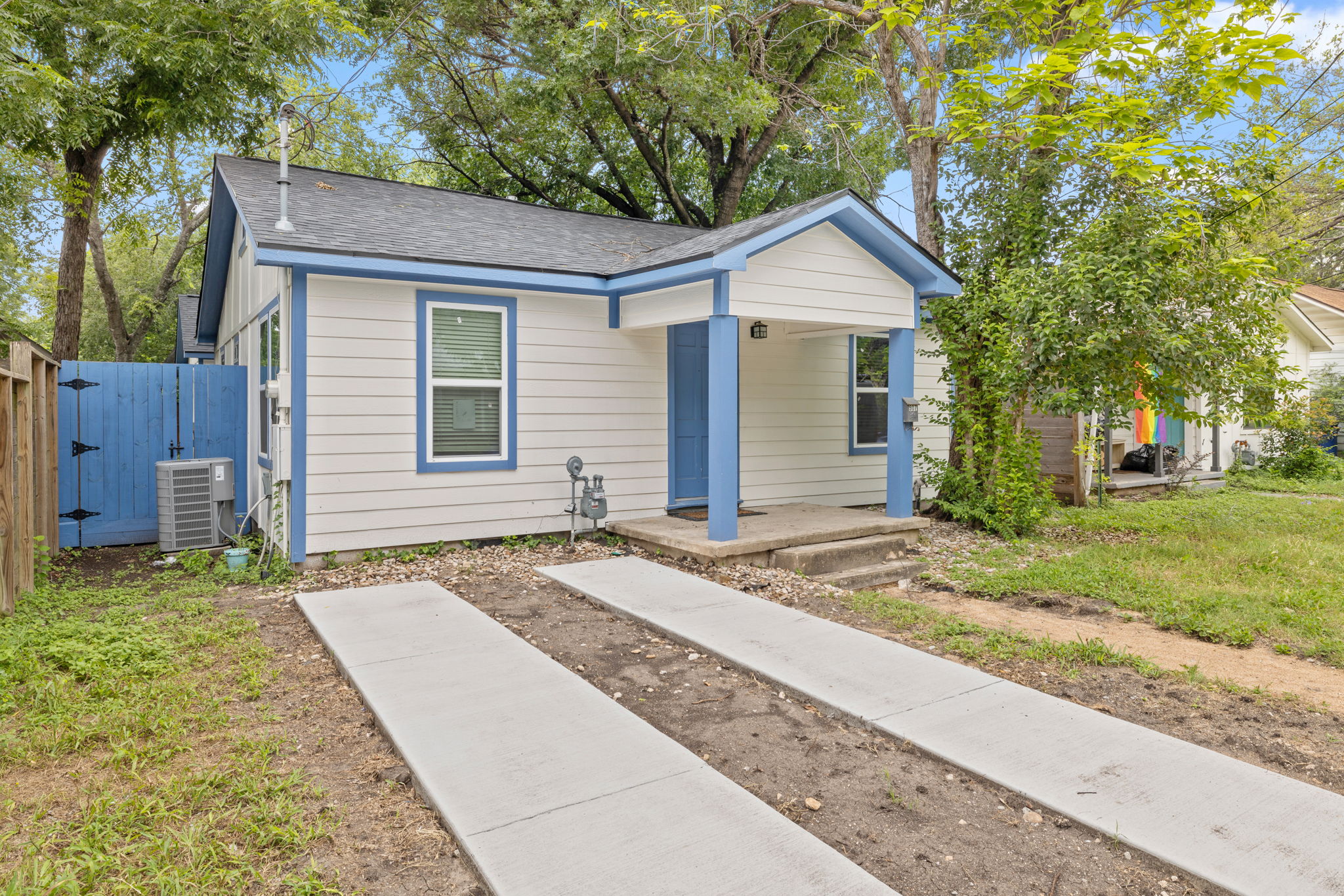 907 East 53rd Street Austin, TX 78751 - Photo 3 of 36 A charming compact home features a simple facade, concrete walkways, and a vibrant blue fence.