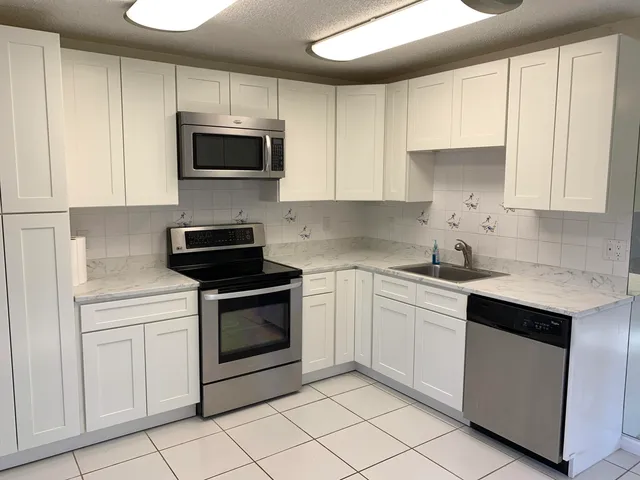a kitchen with granite countertop white cabinets and stainless steel appliances