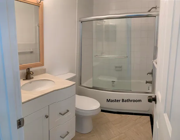 a bathroom with a granite countertop sink toilet a mirror and shower