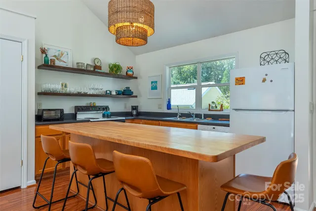a kitchen with stainless steel appliances granite countertop a table chairs stove and sink