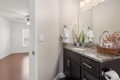 a bathroom with a granite countertop sink toilet mirror vanity and shower