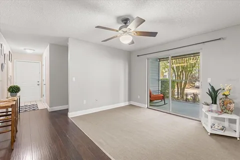 an empty room with wooden floor fan and windows