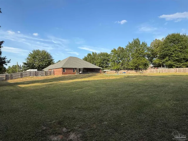a view of a house with a backyard and a large tree