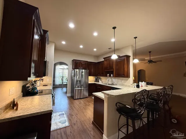 a large kitchen with granite countertop a large counter top a sink stainless steel appliances and cabinets