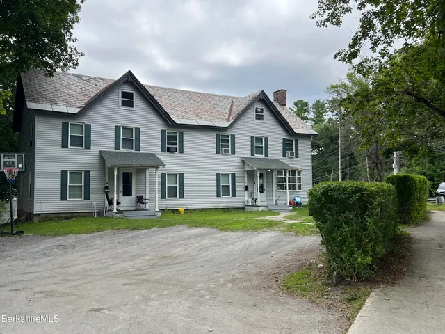 a front view of a house with a garden and trees
