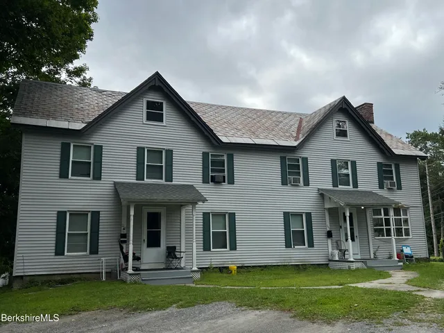 a front view of a house with a yard and trees