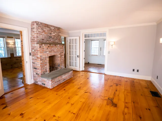 a view of empty room with fireplace and wooden floor