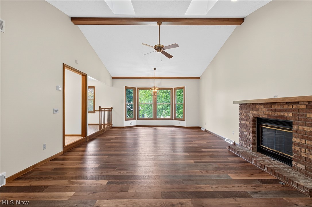 5346 Burlawn Street Northwest Canton, OH 44708 - Photo 7 of 40 Spacious living area featuring wood-finish flooring, a vaulted ceiling with exposed wood beams, and a brick fireplace