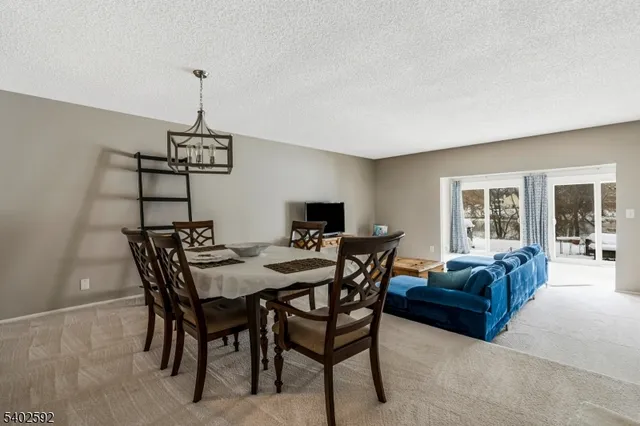a view of a livingroom and dining room with furniture wooden floor a chandelier