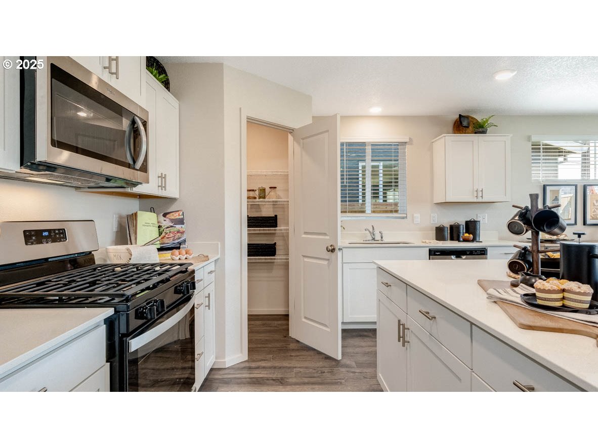 238 Greencrest Street Northeast Salem, OR 97301 - Photo 13 of 26 a kitchen with stainless steel appliances kitchen island granite countertop a stove top oven a sink dishwasher and white cabinets with wooden floor