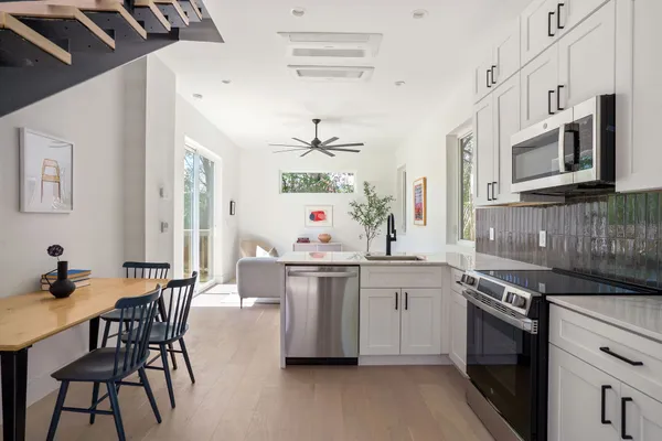 a kitchen with stainless steel appliances a stove a sink dishwasher and white cabinets with wooden floor
