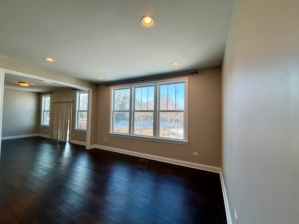 an empty room with wooden floor and windows with curtains