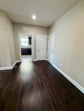 an empty room with wooden floor closet and windows
