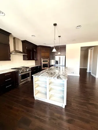 a kitchen with stainless steel appliances kitchen island granite countertop a stove a sink and a wooden floors