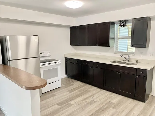 a kitchen with stainless steel appliances kitchen island granite countertop a refrigerator and a sink