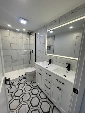 a spacious bathroom with a double vanity sink toilet mirror and shower