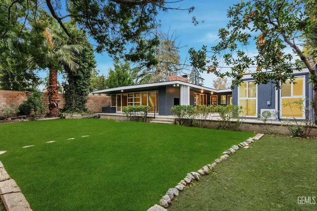 a front view of a house with a garden and trees