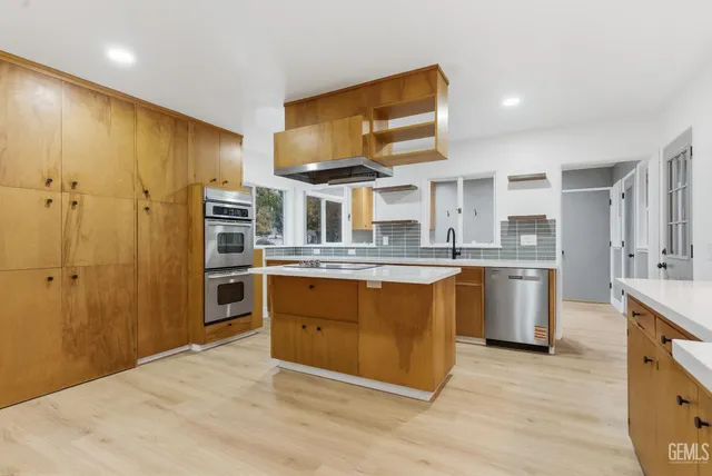 a kitchen with stainless steel appliances granite countertop a sink a stove and refrigerator