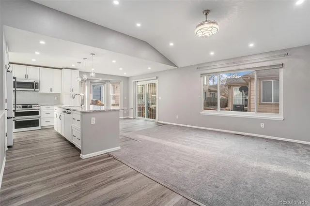 a large kitchen with stainless steel appliances kitchen island a large counter top and wooden floors