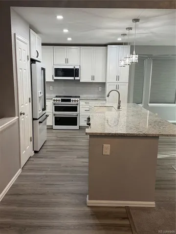 a kitchen with granite countertop a refrigerator stove and sink
