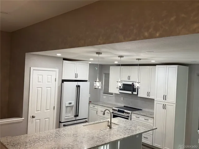 a view of kitchen with sink refrigerator and cabinets