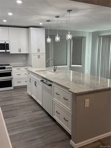 a large kitchen with granite countertop a sink and dishwasher a stove with wooden floor