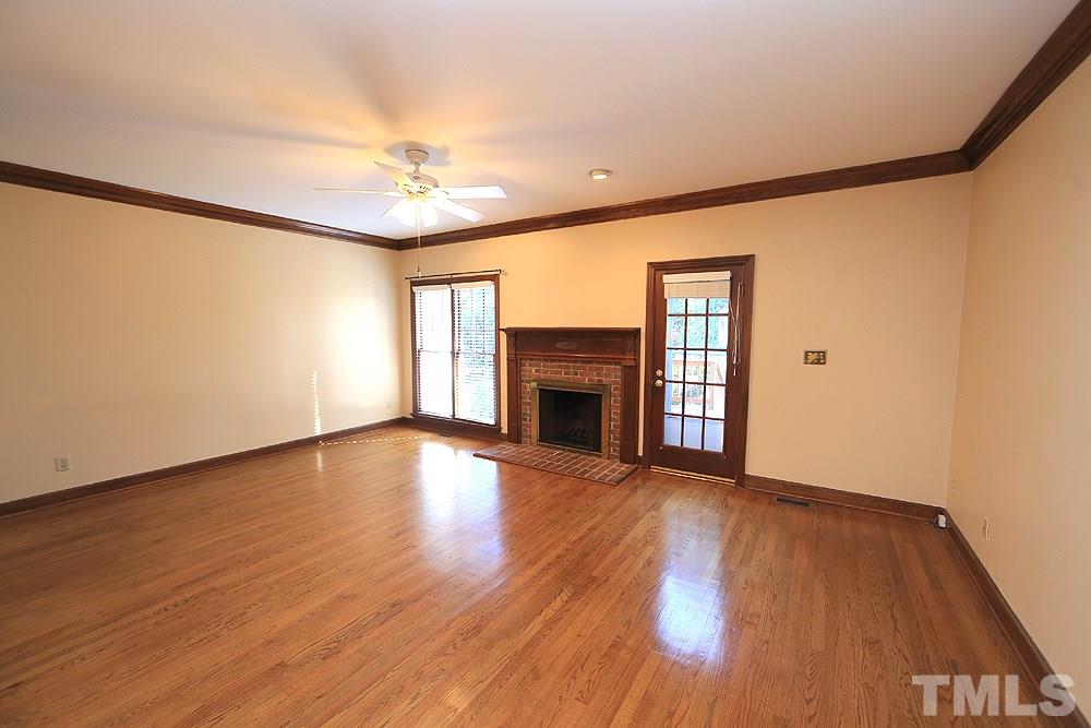 122 Skylark Way Raleigh, NC 27615 - Photo 11 of 30 an empty room with wooden floor fireplace and windows