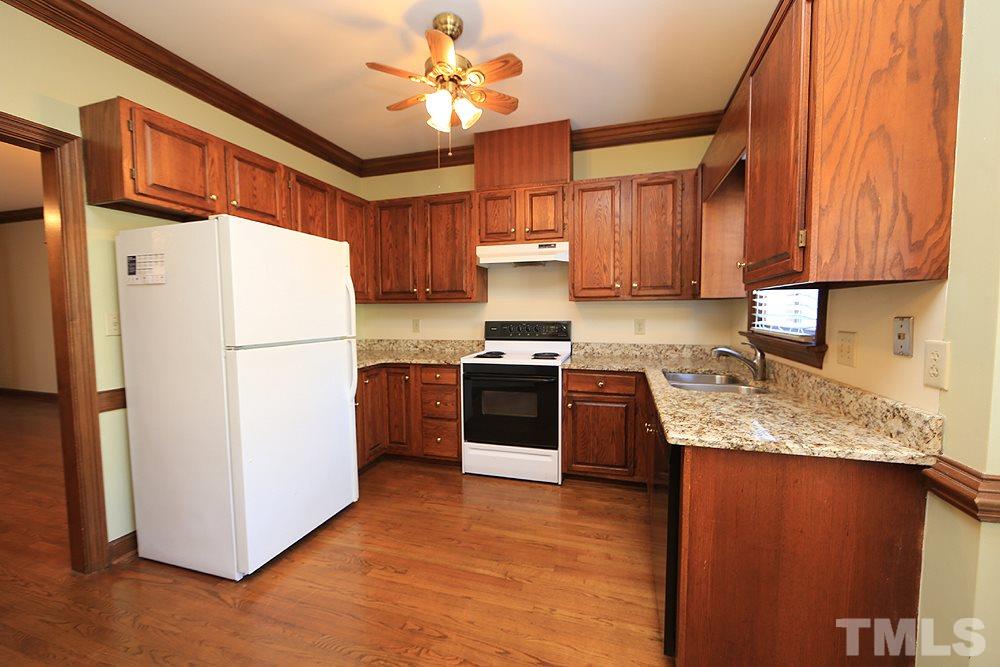 122 Skylark Way Raleigh, NC 27615 - Photo 7 of 30 a kitchen with granite countertop a refrigerator a sink dishwasher and a stove top oven with wooden floor