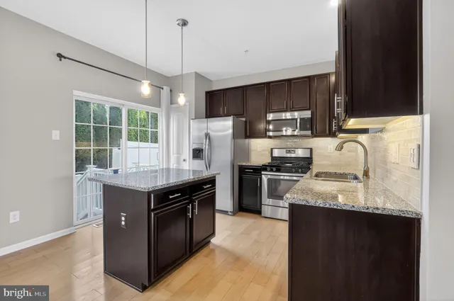 a kitchen with granite countertop stainless steel appliances a stove sink and refrigerator