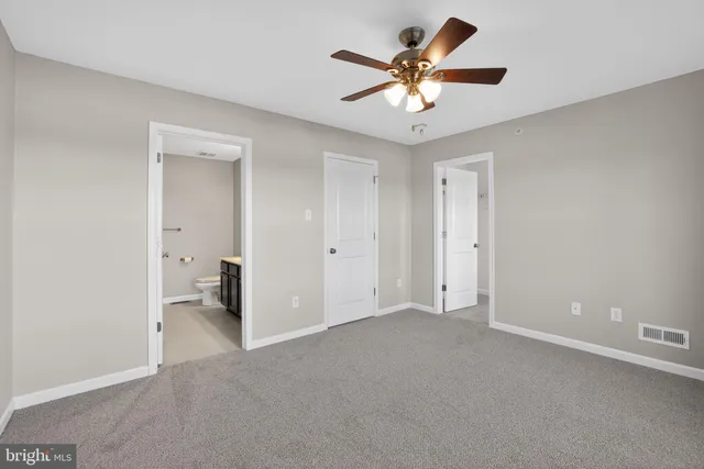 an empty room with windows and chandelier fan