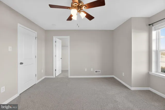 an empty room with a window and a ceiling fan